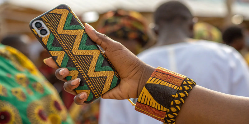 A hand holding a smartphone with a colorful Black art phone grip.