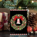 Christmas card with wreath and bell design, surrounded by festive decorations.