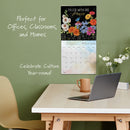 Calendar on a wall with a desk, laptop, and mug in the foreground